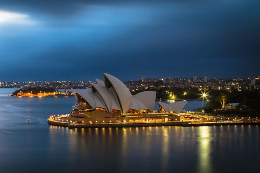 Sydney Opera House lit up beside the harbour at night